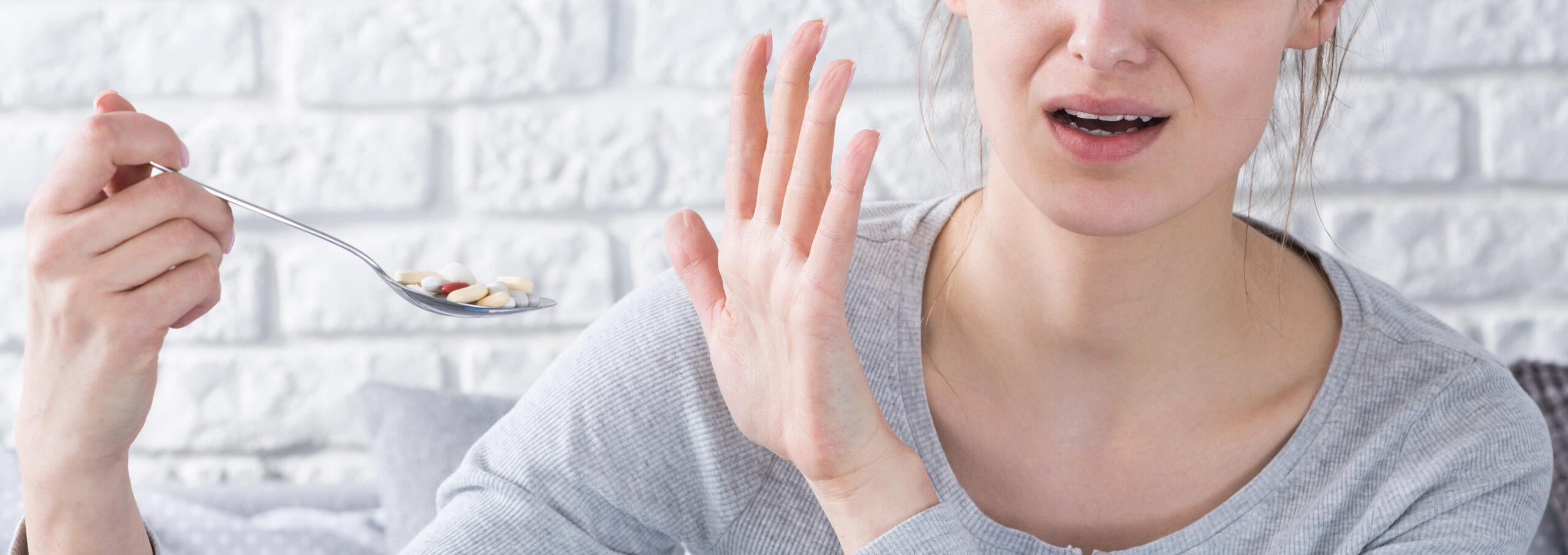 Vrouw trekt vies gezicht en weigert pillen op lepel in te nemen