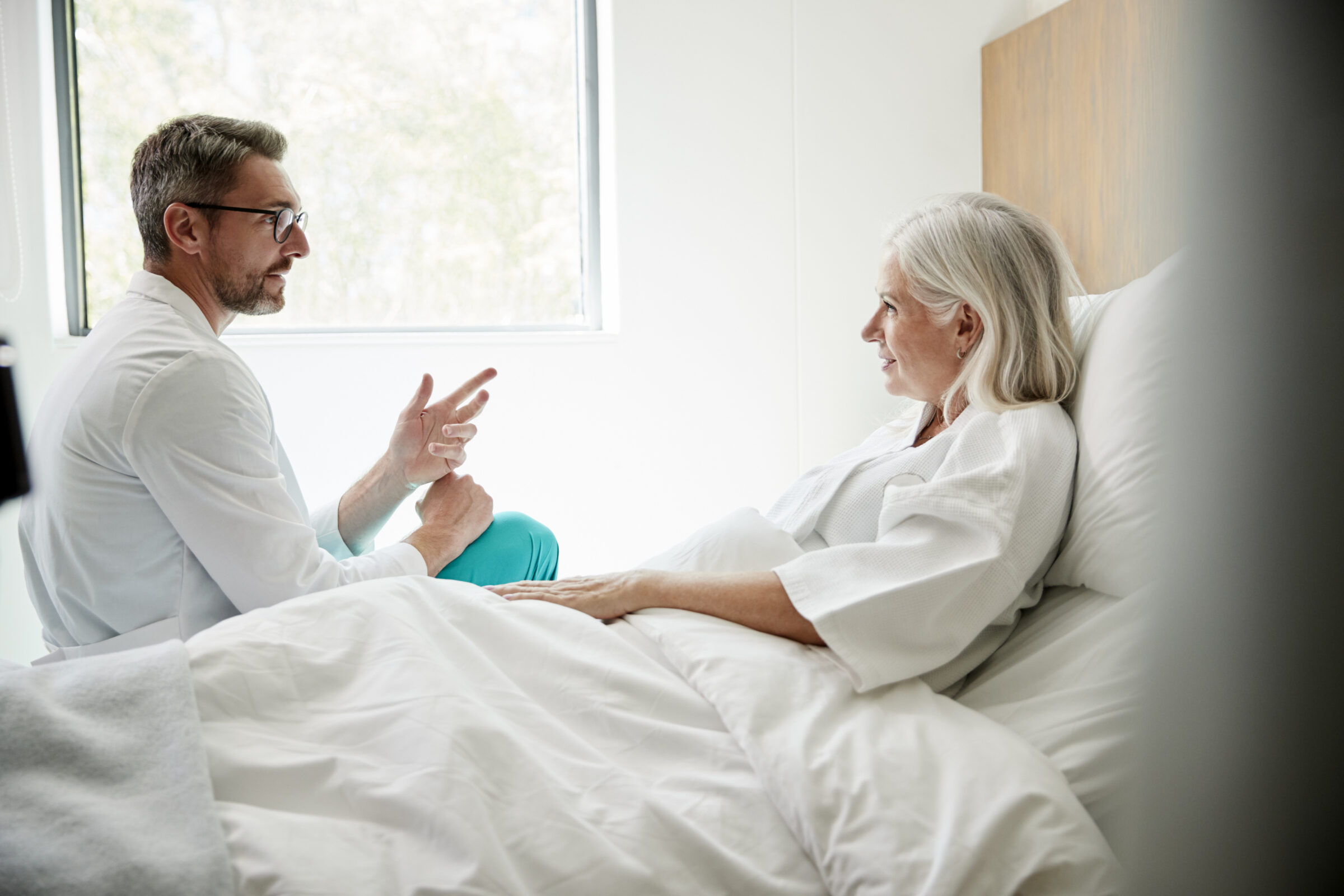 vrouwelijke patiënt in ziekenhuisbed heeft gesprek met dokter