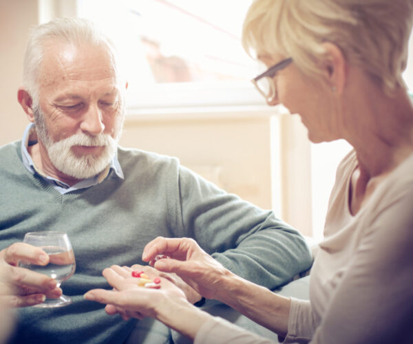 vrouw helpt oude man met pillen uitzoeken