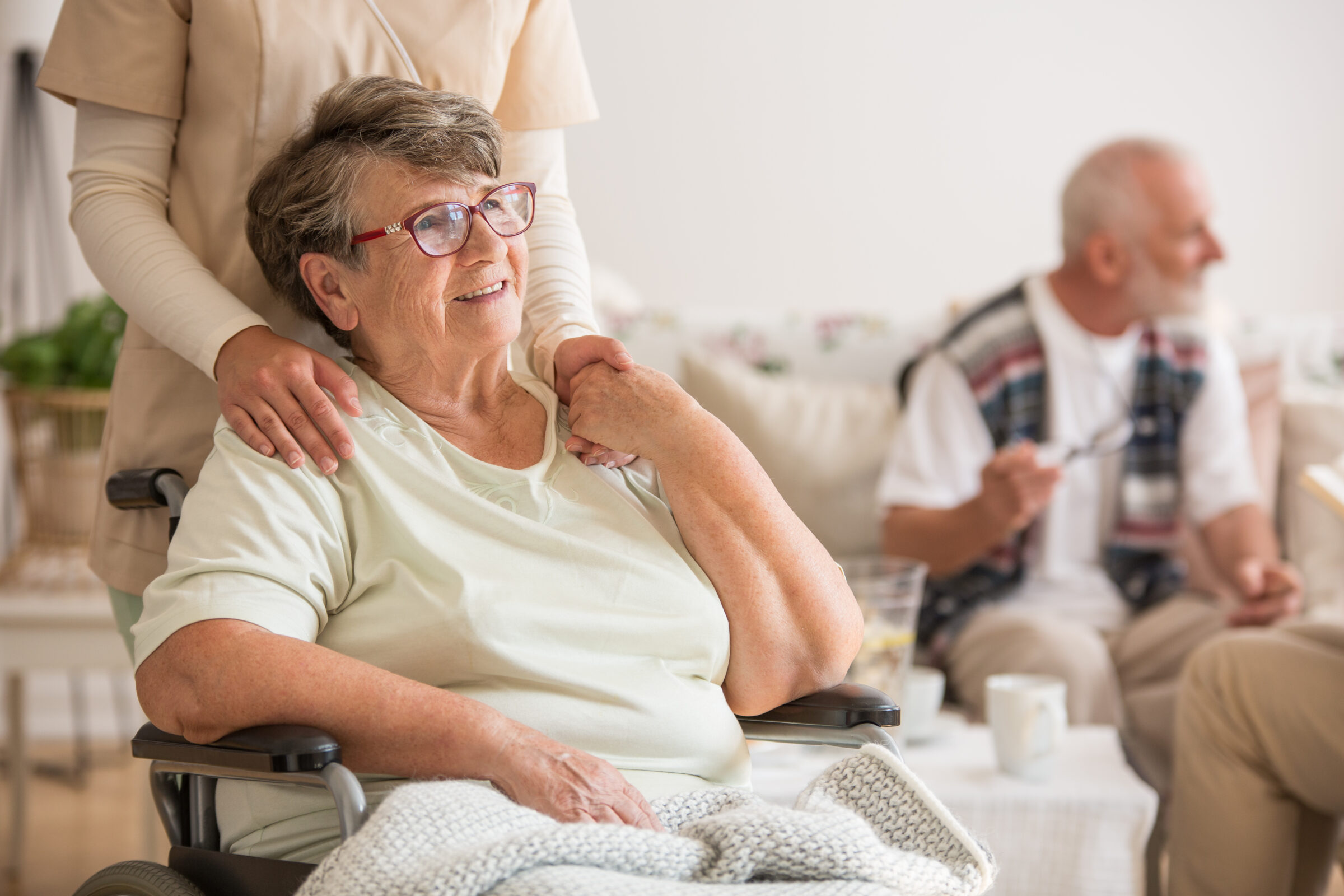 oude dame in rolstoel houdt hand van verpleegster vast