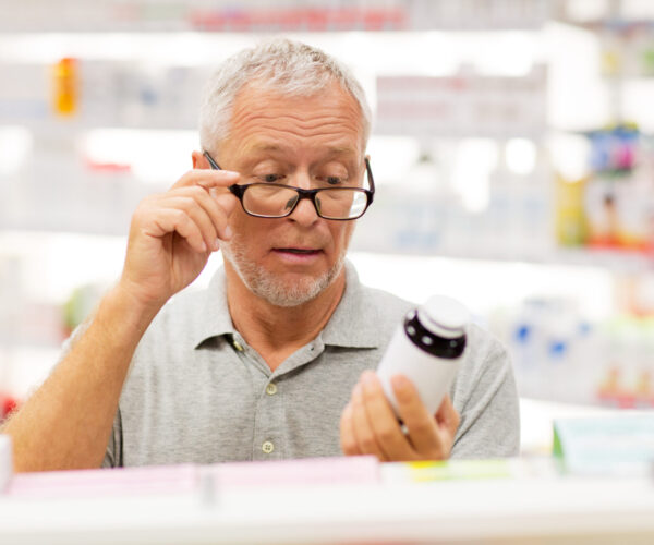 Man met leesbril in de apotheek leest verpakking van pot pillen